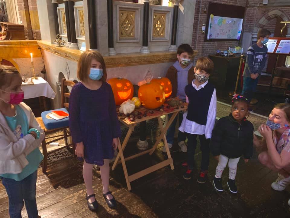 Children posing in front of Jack-o-Lanterns.