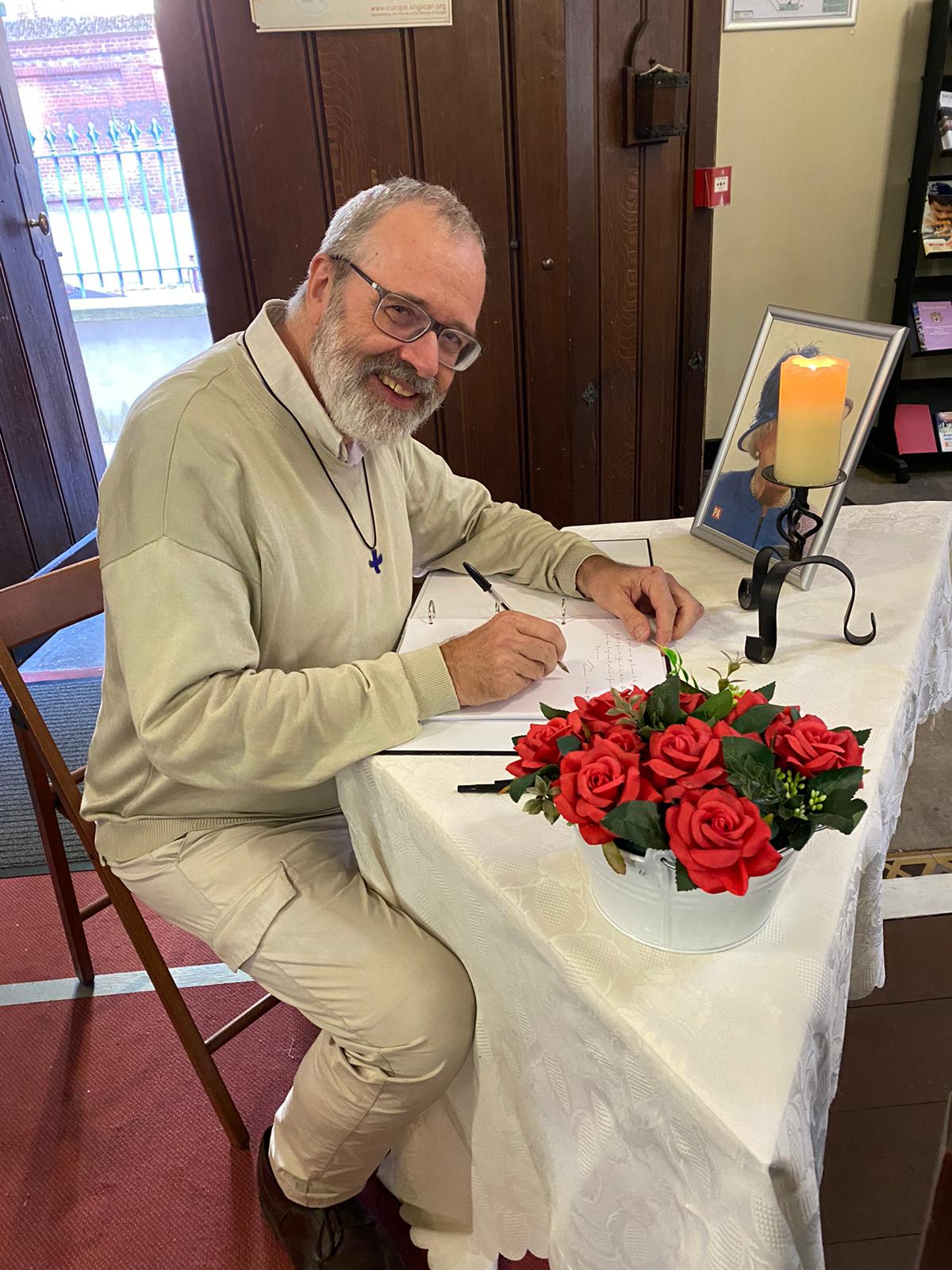 A man writing in a condolences book for the queen.