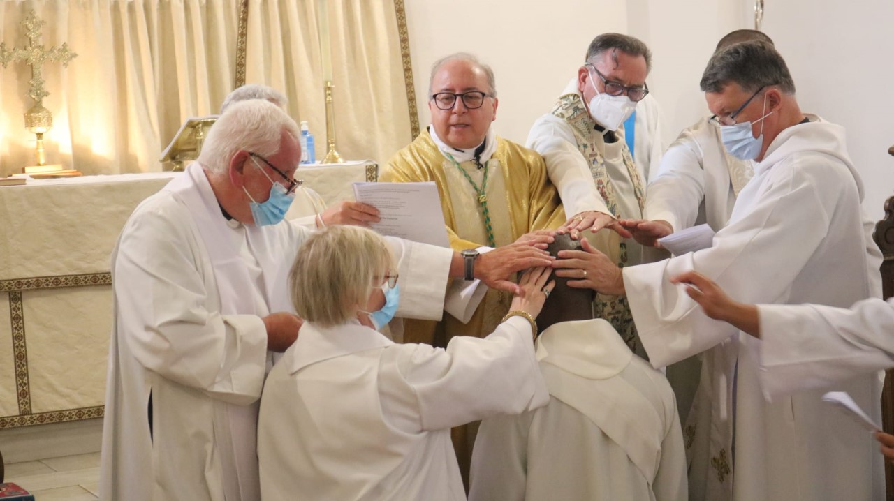 Clergy members placing their hands on anothers head.