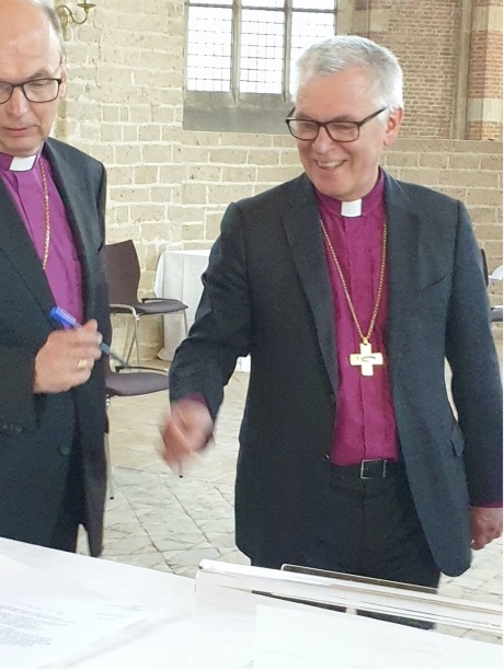 Bishop Dirk Schoon signing a document.
