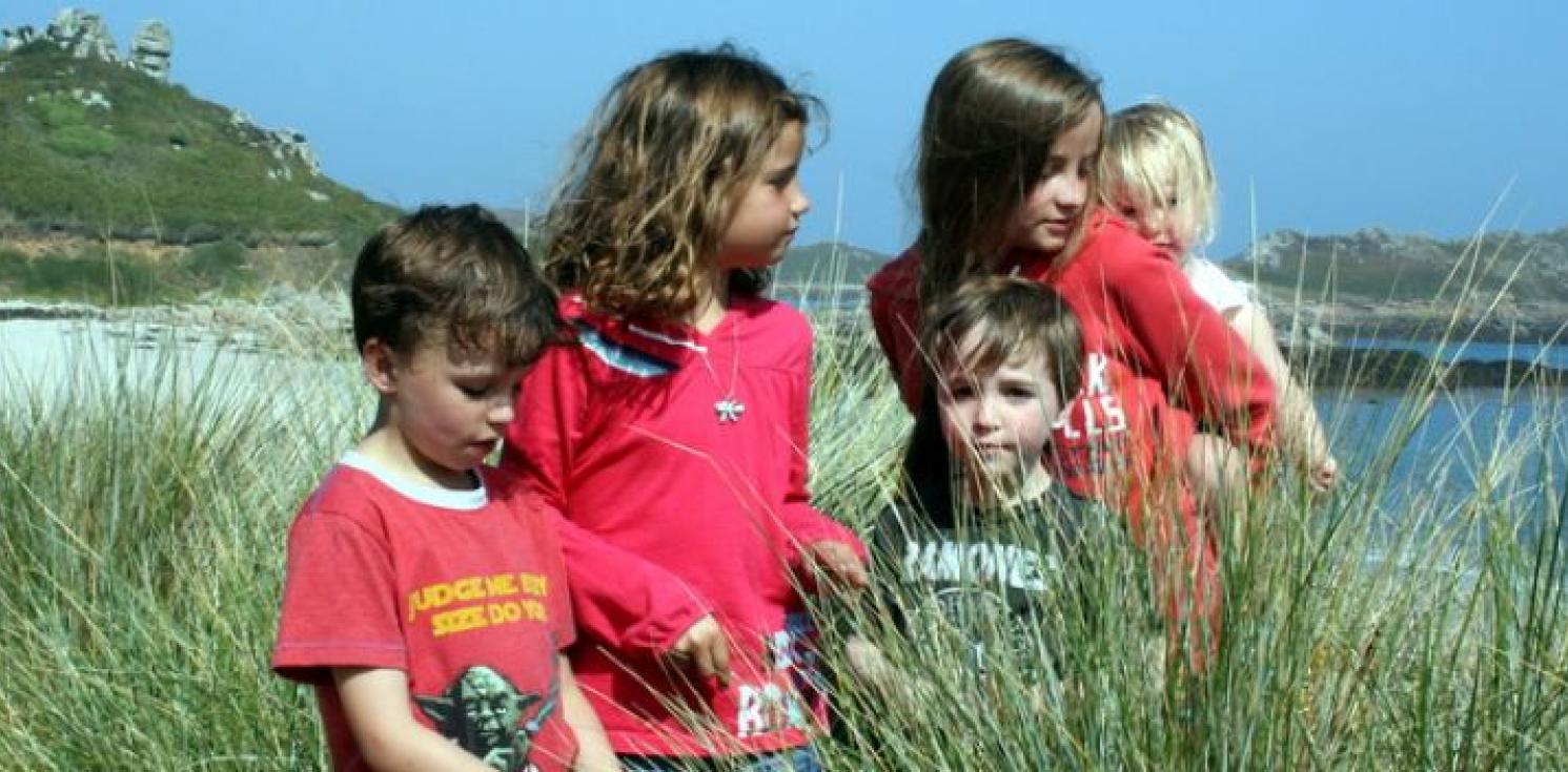 Five children stood on a sunny beach.