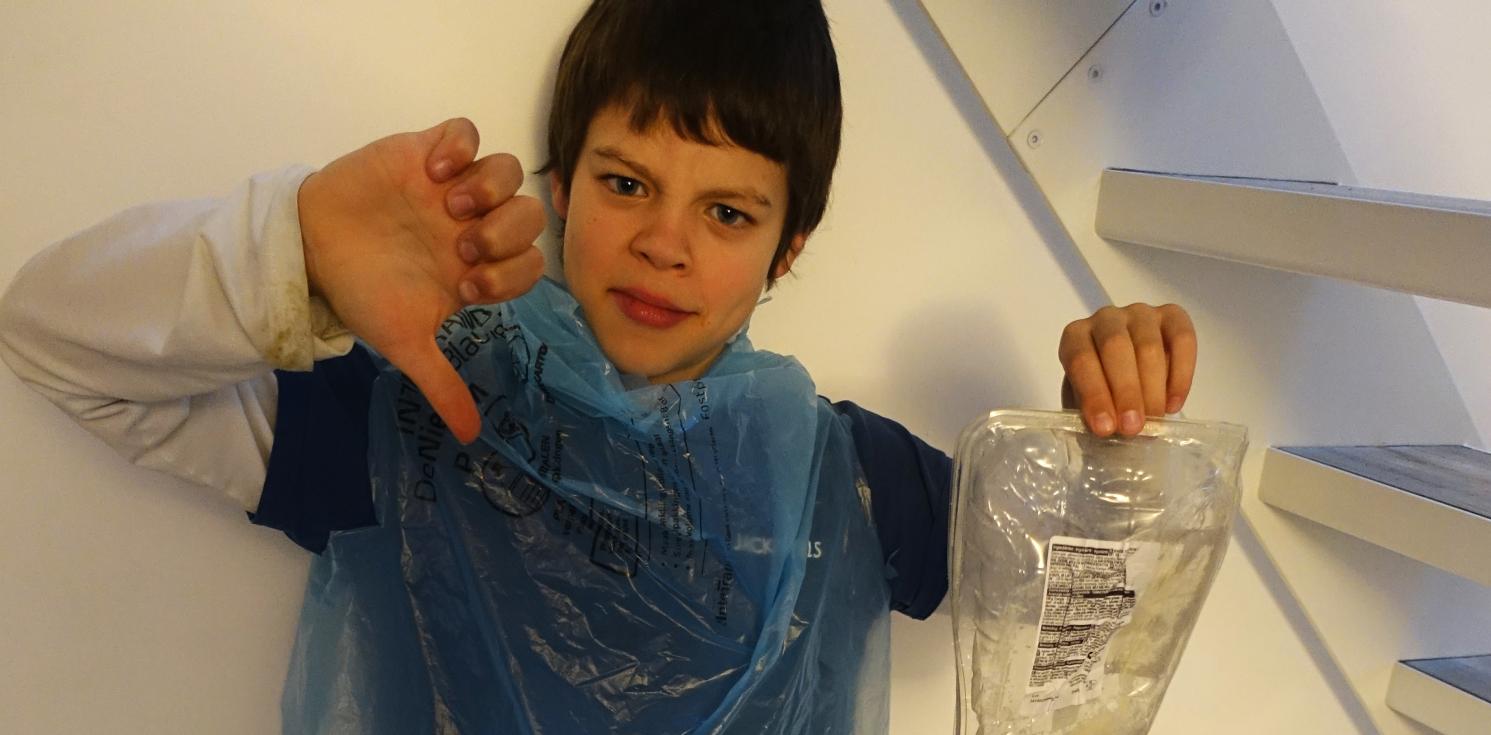 young boy with thumbs down and a plastic bag