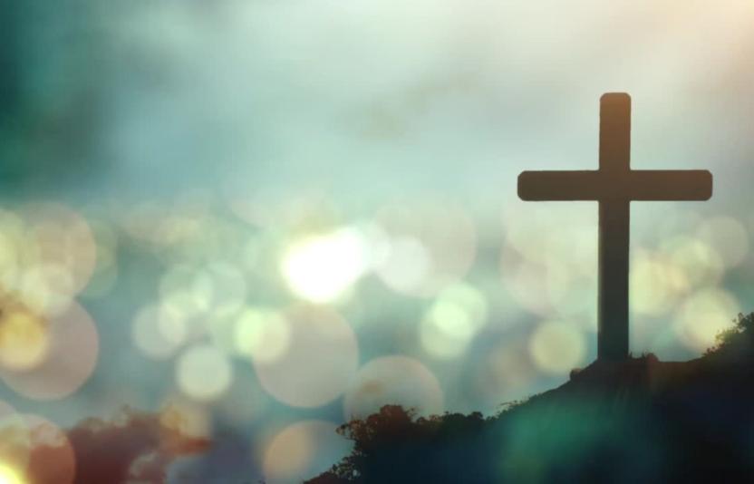 A cross silhouetted against a bokeh sky