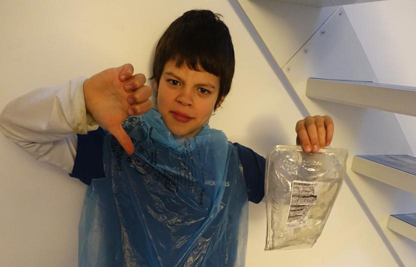 young boy with thumbs down and a plastic bag