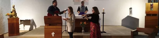 People singing and playing guitar at the front of a church.