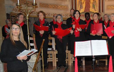 A choir group dressed in red and black stand ready to perform.