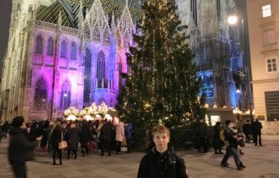 boy standing next to Christmas tress